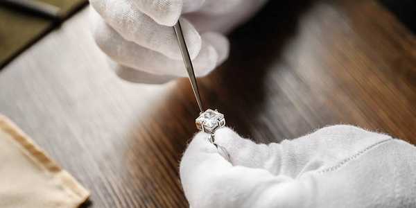 A person checking a diamond on a ring. 